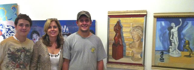 Karen and her sons with Karen's paintings in the Chastain Arts Center gallery.